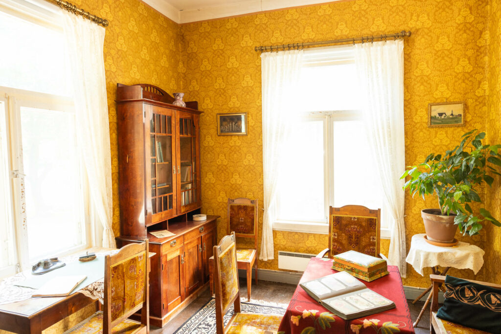 Vanhanaikaisesti sisustettu huone museossa. Ikkunat kahdella seinällä tekevät tilasta valoisan.